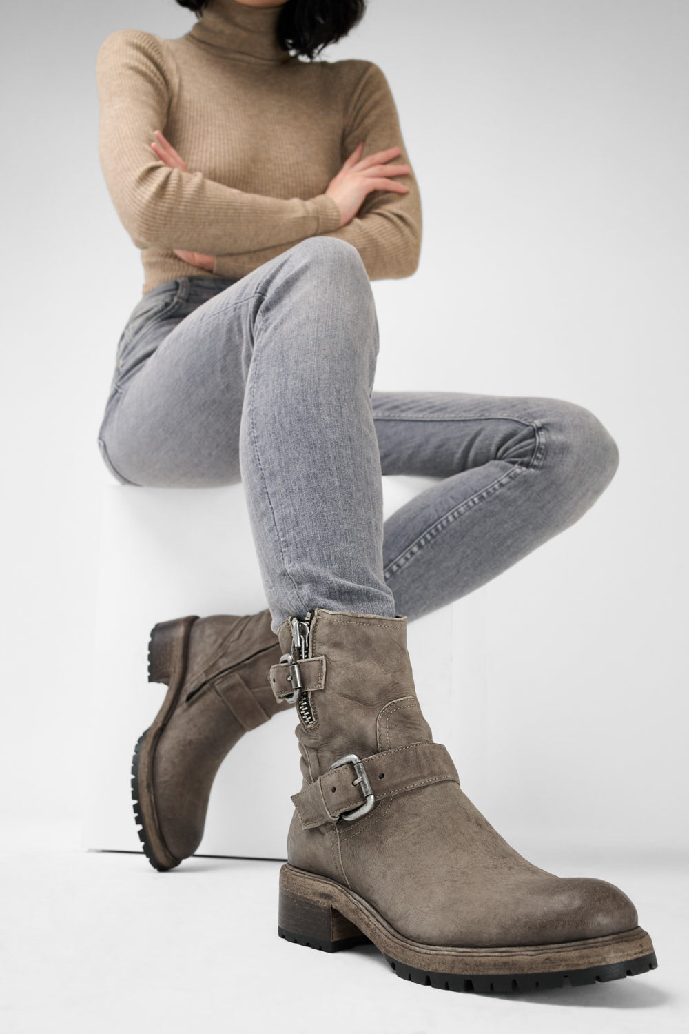 Women wearing graish brown biker  boots with buckles on a white background